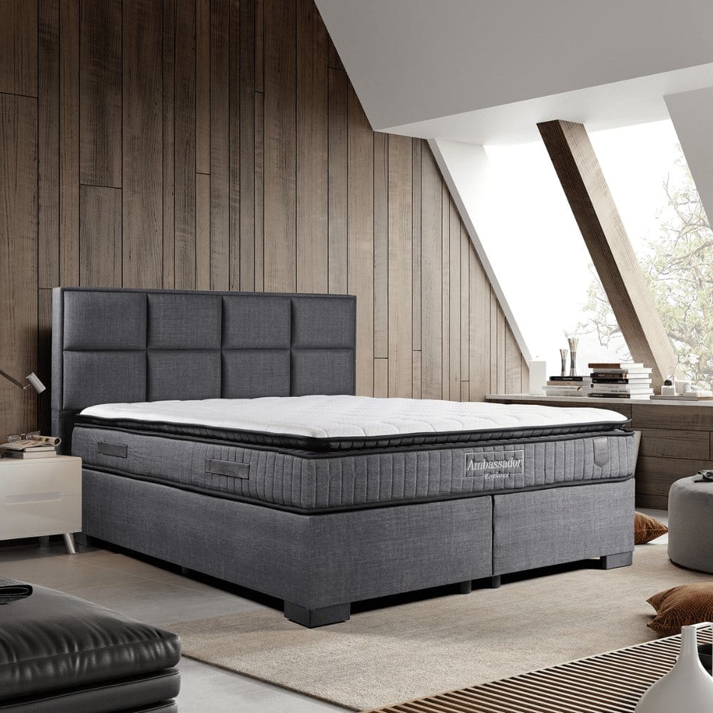 Boxspring met matras en topper in een lichte slaapkamer, te leasen bij Bedden-Lease